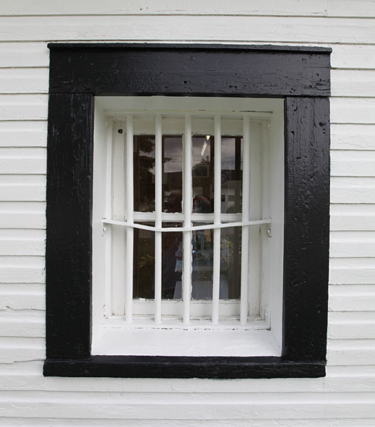 Close up image of one of the windows of the Old Killarney Jail house showing the bars on the window.
