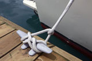 Close up image of a knotted rope line anchoring a boat to the pier.