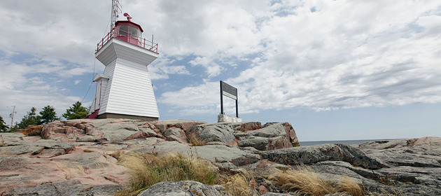 Image of a white red-roofed Killarney East Lighthouse on top of a Red Rock Point.